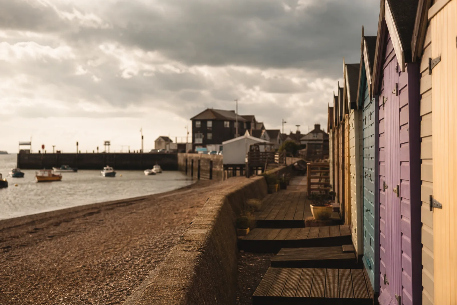 Pastel beach huts along Whitstable seafront looking towards the harbour